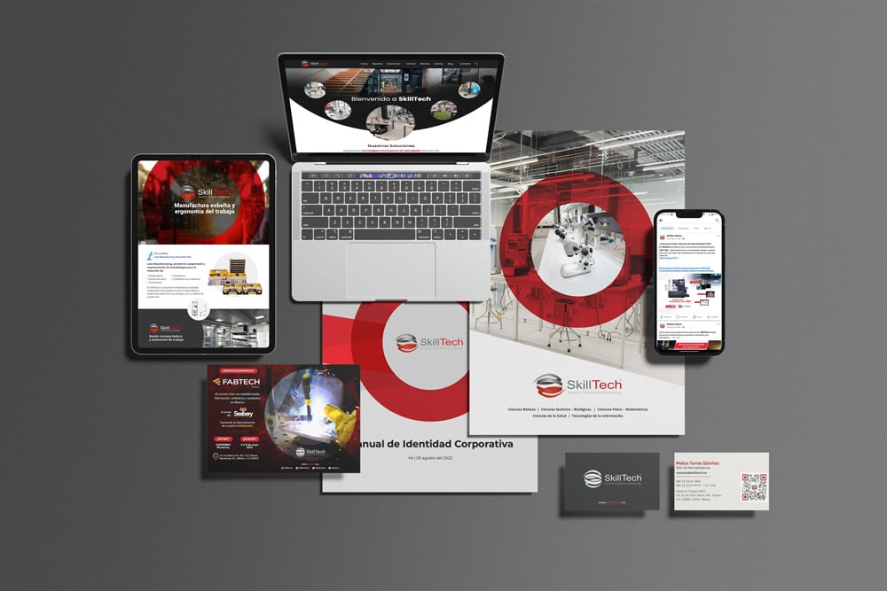 Un diseño de materiales promocionales de SkillTech mostrados en una superficie gris, que incluye una computadora portátil, un folleto, un teléfono inteligente, tarjetas de presentación, un cuadernillo y varios materiales impresos.