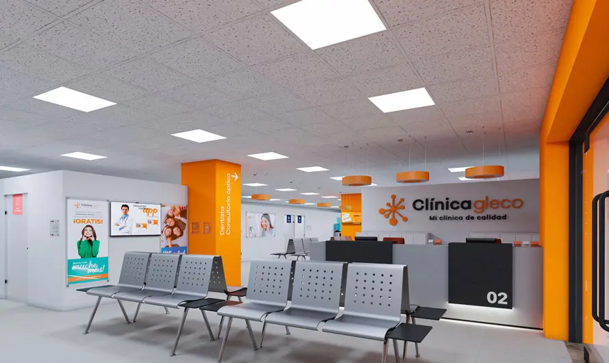 Una moderna sala de espera clínica con decoración naranja y gris, con filas de sillas grises y carteles informativos alineados estratégicamente en las paredes, encarna la estrategia de comunicación de Glecolab, con un elegante mostrador de recepción al fondo.